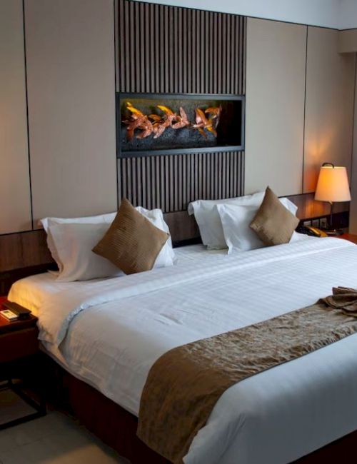 This image shows a cozy hotel room with a large bed, decorative pillows, bedside tables with lamps, and a neat, minimalistic decor.