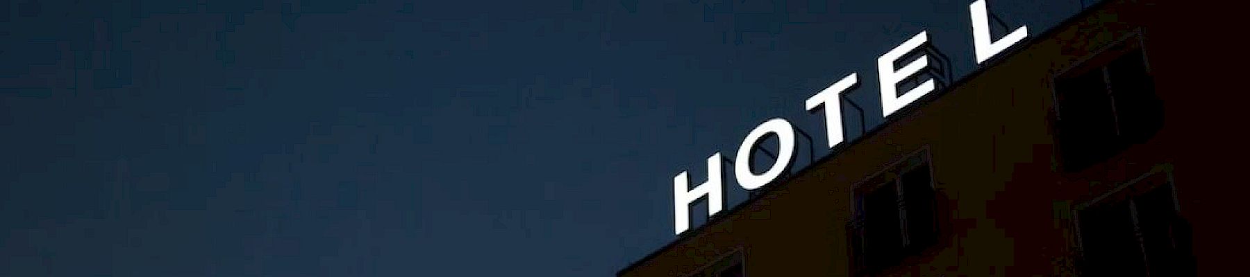 An illuminated "HOTEL" sign is on the corner of a building against a dark sky.